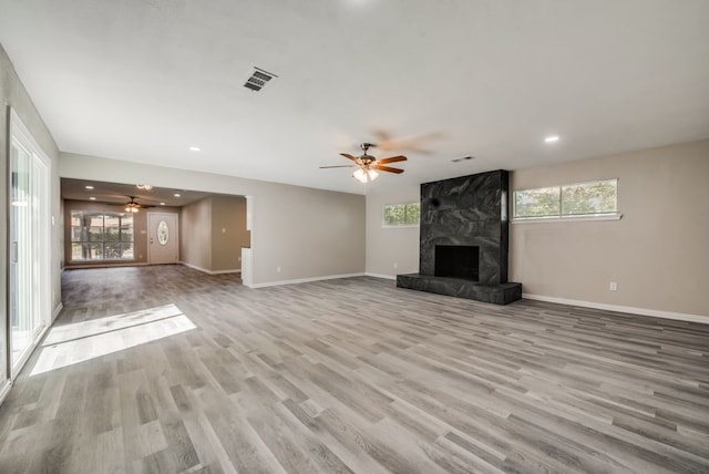 unfurnished living room with plenty of natural light, light wood-style floors, visible vents, and a premium fireplace