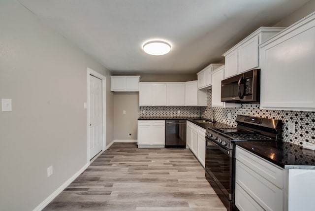 kitchen featuring black appliances, dark countertops, white cabinets, light wood finished floors, and decorative backsplash