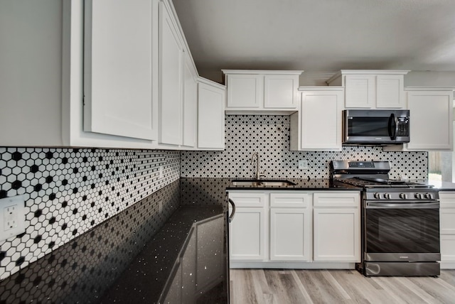 kitchen with a sink, stainless steel appliances, tasteful backsplash, and white cabinets