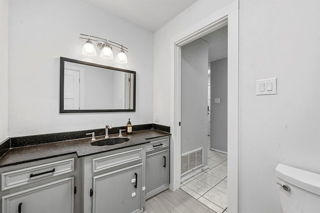 half bathroom featuring tile patterned flooring, visible vents, toilet, and vanity