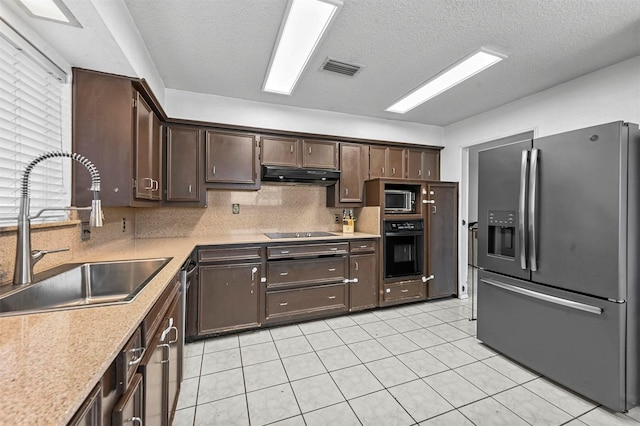 kitchen featuring a sink, black appliances, light countertops, dark brown cabinetry, and under cabinet range hood