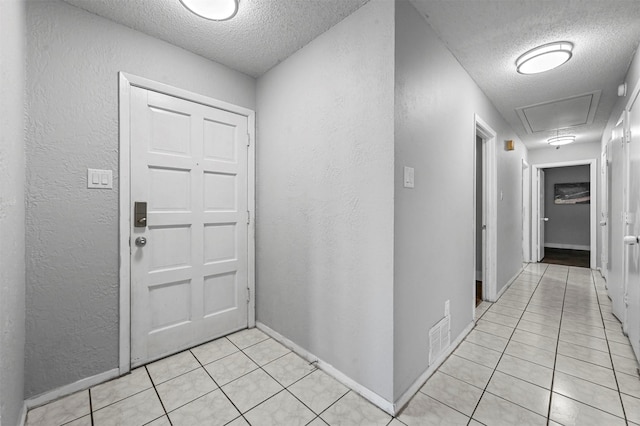 entryway with light tile patterned floors, a textured ceiling, and a textured wall