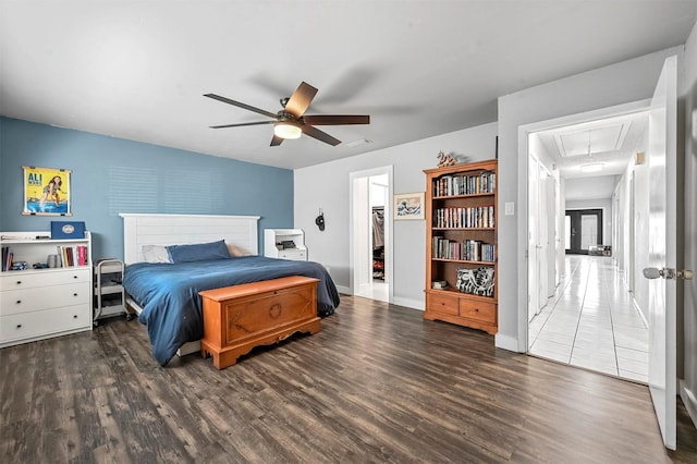 bedroom with visible vents, baseboards, attic access, wood finished floors, and a ceiling fan