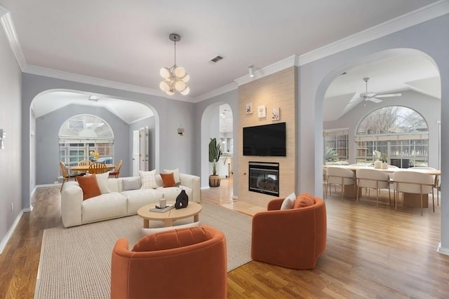 living room with lofted ceiling, wood finished floors, visible vents, and arched walkways