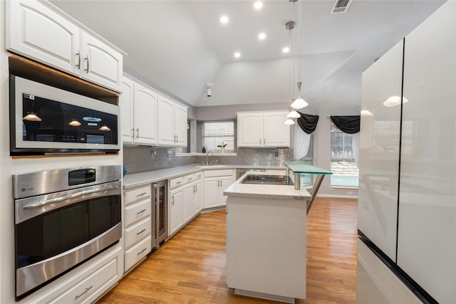 kitchen with visible vents, a sink, white cabinetry, wine cooler, and stainless steel oven