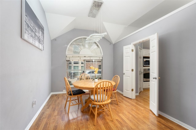 dining area featuring baseboards, lofted ceiling, and light wood-style floors