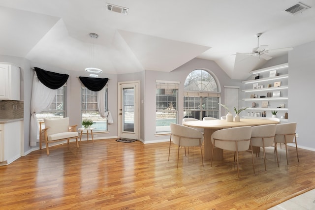 dining area with light wood-type flooring, visible vents, a ceiling fan, and vaulted ceiling