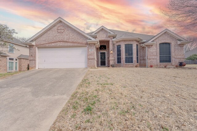 single story home with brick siding, an attached garage, driveway, and a front yard