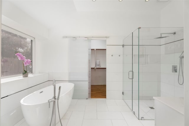 full bath with tile patterned flooring, a shower stall, a freestanding bath, and tile walls