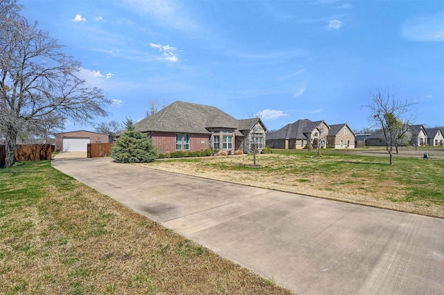 view of front of house featuring an outbuilding, a front lawn, fence, a garage, and brick siding