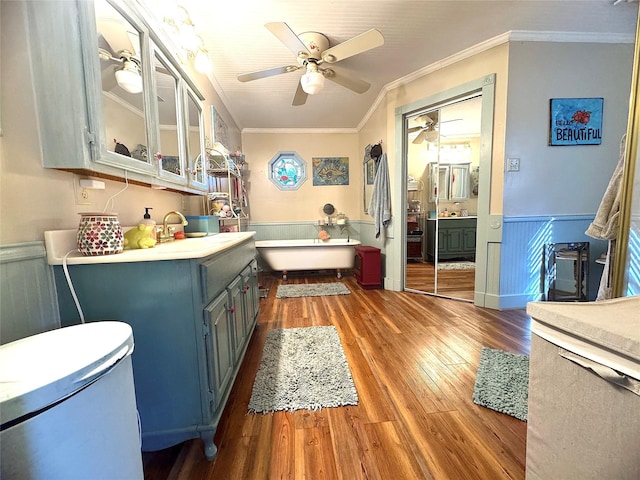 bathroom featuring a freestanding tub, a wainscoted wall, wood finished floors, crown molding, and vanity