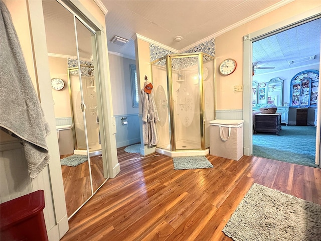 bathroom featuring wood finished floors, visible vents, a stall shower, wainscoting, and crown molding