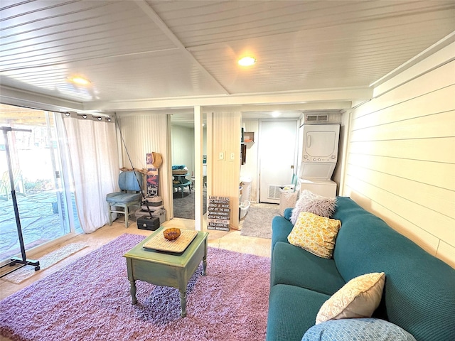 living room with visible vents, wooden walls, wooden ceiling, and stacked washer / dryer