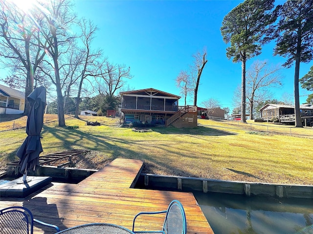 dock area with a lawn, a deck, stairs, and fence