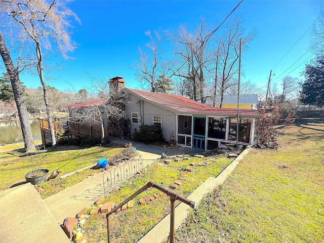 view of front of property with a chimney, a front yard, and a sunroom