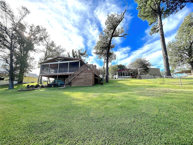 view of yard featuring fence, stairs, and a sunroom