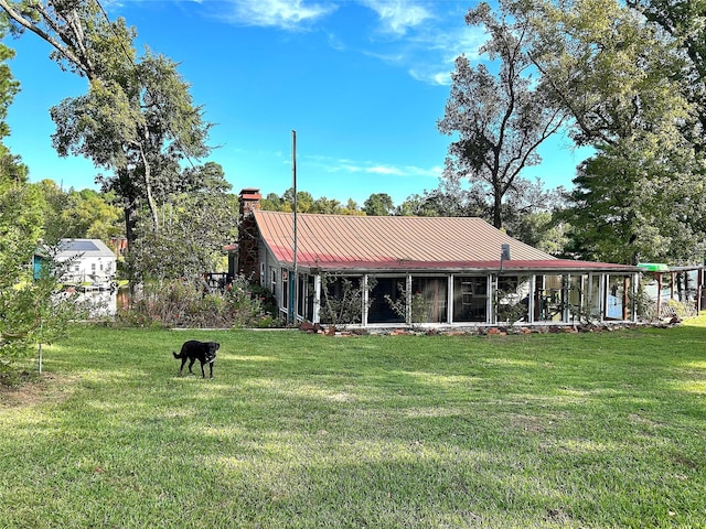 back of property featuring metal roof, a lawn, and a chimney