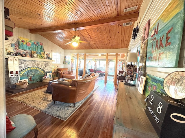 living room with visible vents, a fireplace, wood finished floors, and vaulted ceiling with beams