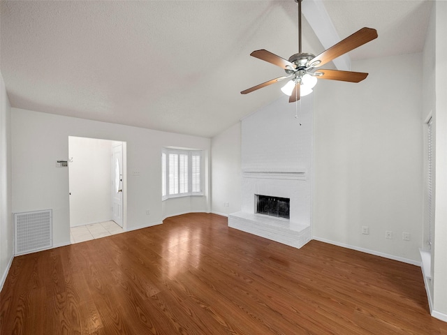 unfurnished living room with visible vents, baseboards, lofted ceiling, a fireplace, and wood finished floors