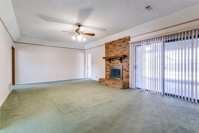 unfurnished living room with visible vents, carpet flooring, a fireplace, a textured ceiling, and a ceiling fan