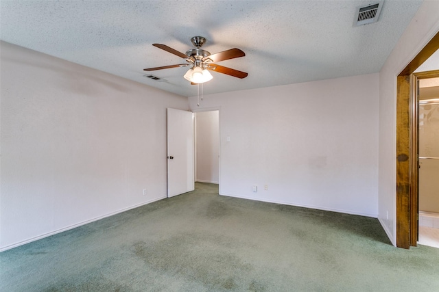 unfurnished room with carpet flooring, visible vents, and a textured ceiling