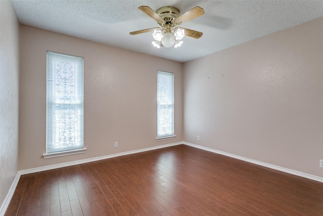 unfurnished room with a wealth of natural light, ceiling fan, and dark wood-style flooring