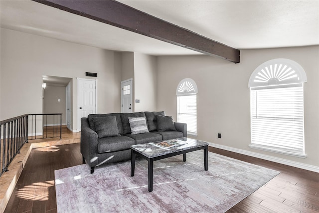 living room featuring vaulted ceiling with beams, baseboards, and wood finished floors