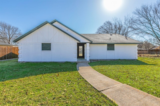 view of front of home featuring a front lawn, fence, board and batten siding, and roof with shingles