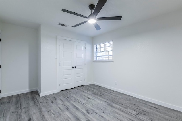 unfurnished bedroom with visible vents, wood finished floors, a closet, baseboards, and ceiling fan