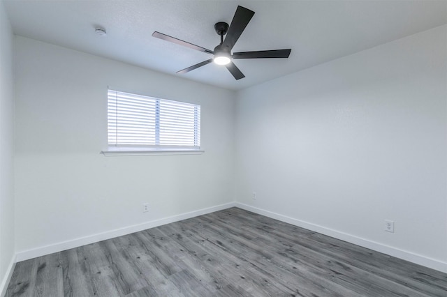 unfurnished room featuring a ceiling fan, wood finished floors, and baseboards