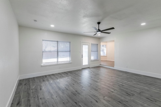 interior space featuring baseboards, dark wood-type flooring, a healthy amount of sunlight, and a textured ceiling