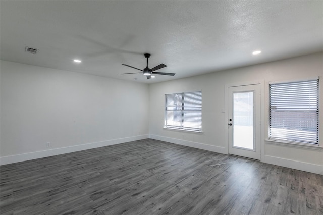 spare room featuring dark wood-style floors, visible vents, baseboards, recessed lighting, and a textured ceiling