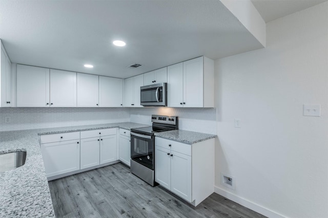 kitchen with baseboards, visible vents, light wood-style flooring, stainless steel appliances, and white cabinets