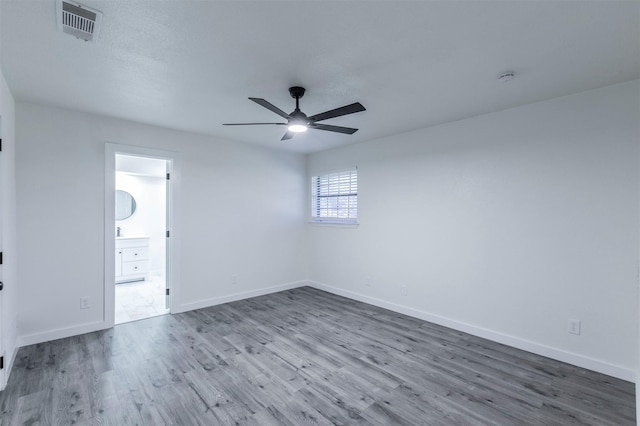 spare room with visible vents, a ceiling fan, baseboards, and wood finished floors