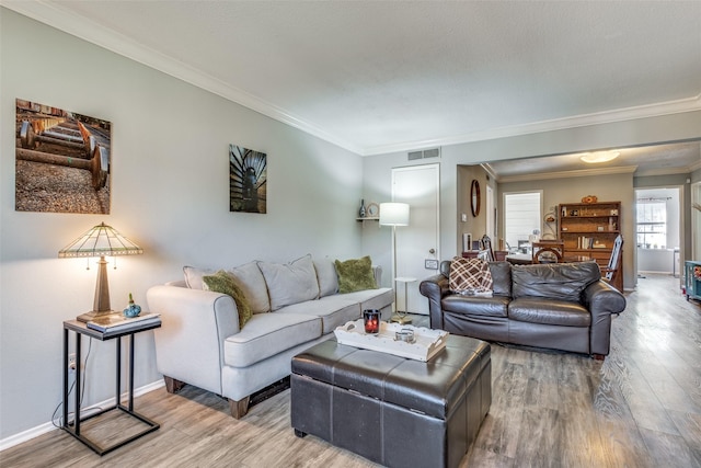 living area featuring wood finished floors, visible vents, and ornamental molding