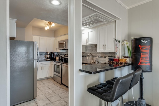 kitchen with a sink, appliances with stainless steel finishes, a breakfast bar area, and white cabinetry