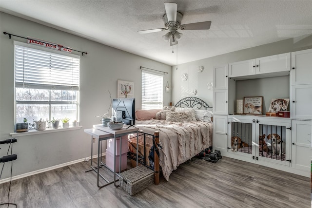 bedroom with a ceiling fan, wood finished floors, baseboards, and a textured ceiling