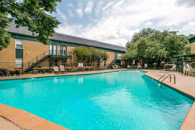 pool with a patio area, stairs, and fence