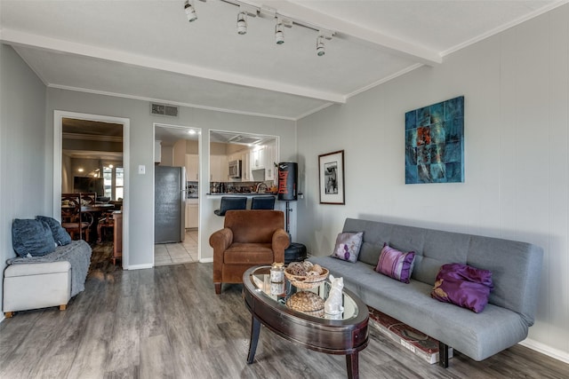 living room with visible vents, beam ceiling, wood finished floors, and ornamental molding