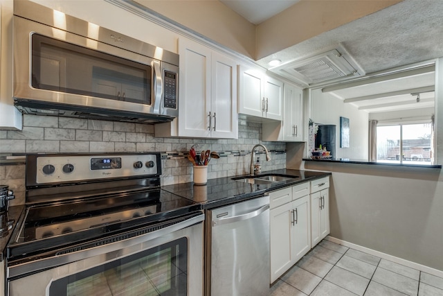 kitchen with light tile patterned floors, appliances with stainless steel finishes, white cabinetry, and a sink