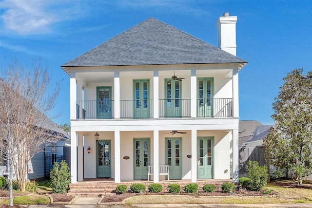 view of front of property featuring a porch, french doors, a shingled roof, a balcony, and a chimney