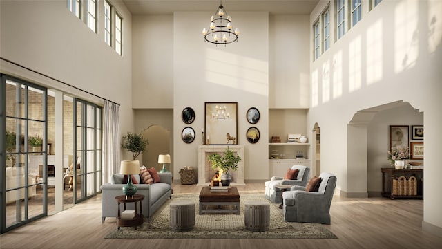 living room featuring an inviting chandelier, wood finished floors, arched walkways, and baseboards