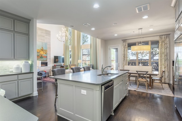 kitchen with a sink, visible vents, stainless steel dishwasher, and dark wood finished floors