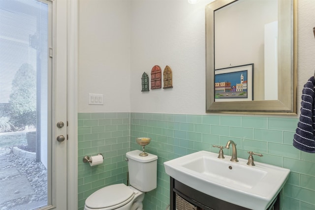 half bathroom featuring wainscoting, vanity, toilet, and tile walls