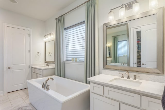 bathroom with a sink, a freestanding tub, two vanities, and marble finish floor