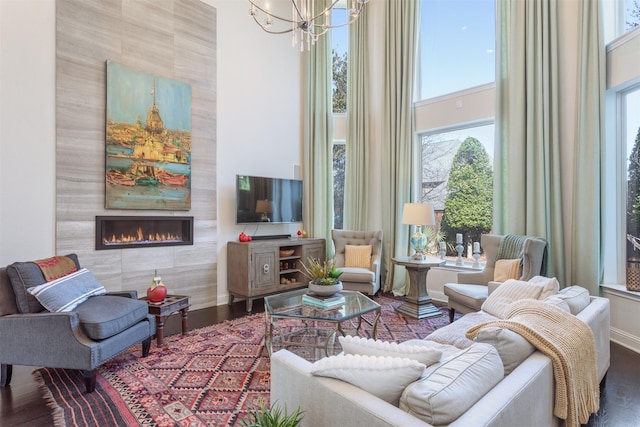 living room featuring a chandelier, a tile fireplace, a towering ceiling, and wood finished floors