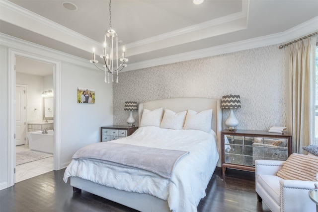 bedroom with wood finished floors, wallpapered walls, ensuite bath, crown molding, and a raised ceiling