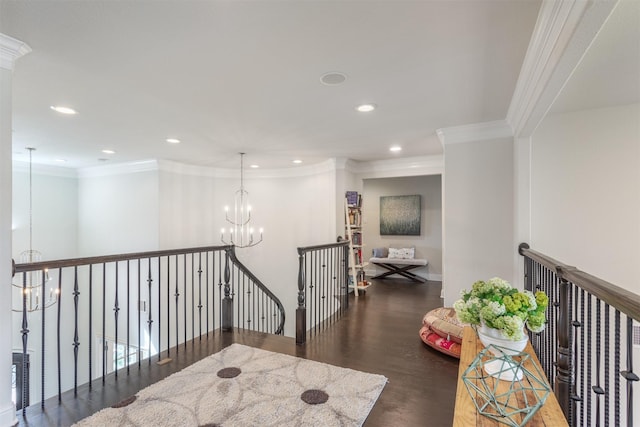 hall with an upstairs landing, wood finished floors, an inviting chandelier, and ornamental molding