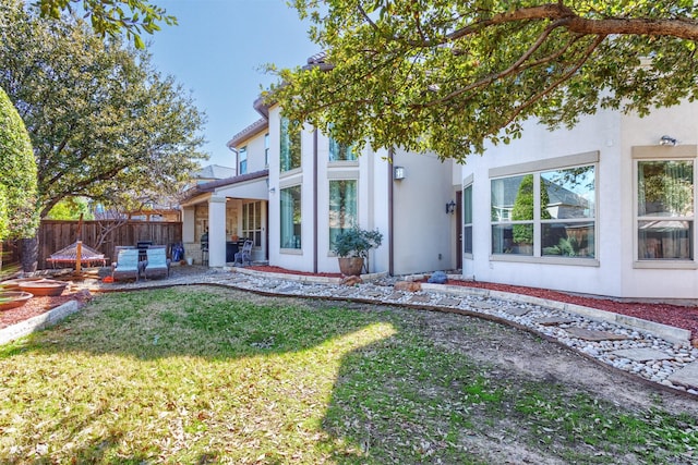 back of house featuring stucco siding, a patio, a yard, and fence