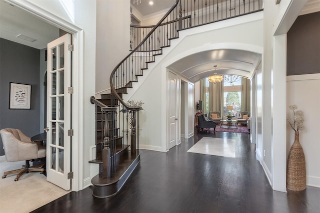 foyer featuring wood finished floors, arched walkways, and baseboards